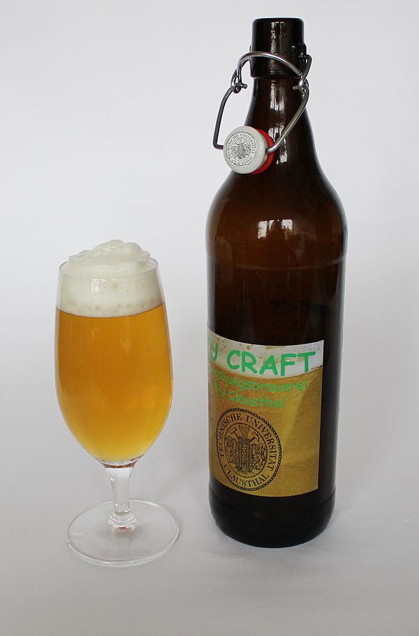 Links ein gefülltes Bierglas mit Schaumkrone, rechts Bierflasche mit geöffnetem Bügelverschluss